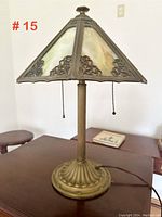 Full view of iron and brass lamp with stained glass shade on a wooden surface