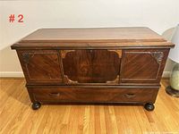 Front view of the vintage solid mahogany chest showing panel details, drawer handles, and overall structure.