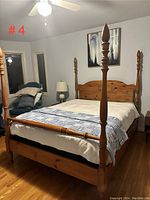 Perspective view of four-poster bed showing placement in room, detailing on posts, and mattress with bedding.