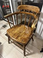 Front and right side view of solid wood antique captain's chair showing worn finish and armrest details