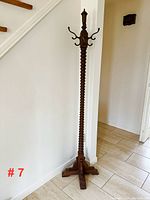 Full view of the wooden coat tree showing the corded spiral design on the post and the four-legged base