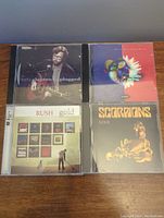 Top view of the four CD cases showing cover artwork for Scorpions Gold, Rush Gold, Dave Matthews Crash, and Eric Clapton Unplugged.