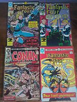 Top view of four French comics: three Fantastic Four and one Conan le Barbare on wooden surface.