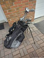 Complete golf club set in Top Flite bag standing on brick surface, showing clubs and bag details.