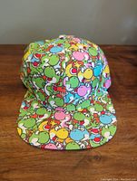 Front view of the colorful Yoshi-covered hat showing the flat brim and bright pattern.