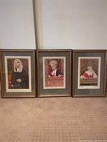 Three framed caricature art pieces of judges by Ralph Sallon arranged side by side on carpeted floor.