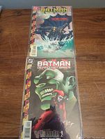 Two Batman Detective Comics issues, one depicting Joker and Harley Quinn, the other Batman in water with a 'Homecoming' storyline, both bagged.