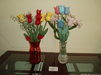 Two faux floral arrangements with wooden tulip stems and filler flowers in distinct glass vases