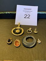 Image showing all seven assorted necklace pendants arranged on black surface with auction tag