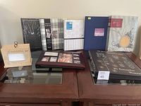 Overview of all eight photo albums arranged on a wooden table showing different cover designs including floral and wood styles.