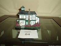 Front view of miniature winter home model with detailed windows, chimney and surrounding shrubbery.