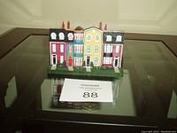 Miniature St. John's rowhouses model displayed on glass table with auction lot number card in front.