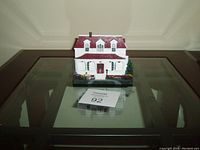 Front view of white ceramic house figurine with red roof and details showing