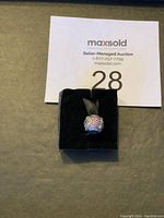 Close-up front view of Pandora bead charm sitting on black display cushion showing sparkling multicolor crystals.