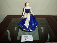 Front view of Royal Doulton Pretty Ladies Olivia figurine wearing a royal blue strapless dress with floral shawl detail, displayed on a glass table.