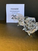 Close-up photo of the Swarovski crystal flower figurine showing rose bloom, faceted leaves, and stem on black background with auction card visible.