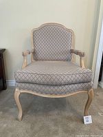 Side view of one patterned wing chair showing wooden frame and diamond-patterned fabric upholstery.
