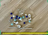 Two sets of IKEA decorative string lights with spherical covers in blue, white, and turquoise colors, each with a white power adapter, laid out on a wooden floor.