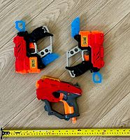 Photo showing two smaller Nerf blasters red and black with blue accents, measured about 12-13 inches long