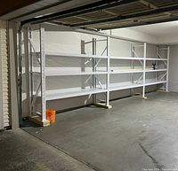 Four-span white powder-coated steel shelving installed in garage, showing uprights, beams and shelf panels