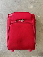 Top view of red Delsey cabin luggage showing fabric exterior with wheels and retractable handle, some small marks visible