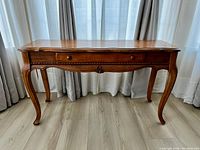 Front view of solid oak console table showing curved legs, carved detail on apron, single drawer with wooden knob, and rounded edges.