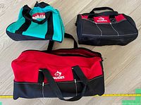 Three tool bags on floor: two Husky brand, one red large and one black small, and one blue-green Makita bag, all unused.