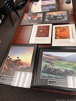 Overview of seven framed motivational posters arranged on a table showing images of mountains, flowers, and golf course with motivational words.