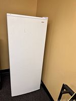 Photo of a white Kenmore refrigerator against a beige wall, showing front and partial side view.