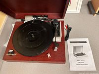 Top down image of USB turntable on wooden base with cables and manual included.