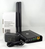 Baxter 5C6M70 4G modem with two antennas and power adapter in front of the NetCommWireless Universal 4G Modem Power Cord box.