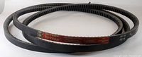 Two black cogged Gates Tri-Power BX116 V-belts with red printed markings coiled on a white background