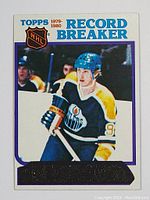 Front of 1980-81 Topps Wayne Gretzky Record Breaker hockey card showing Gretzky in Edmonton Oilers uniform with NHL logo, Topps branding and unscratched gold foil sticker.
