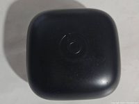 Closed black charging case with Beats logo on top