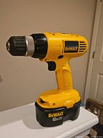 Side view of yellow DeWalt DW929 cordless drill driver with 18V battery attached at base, showing overall condition and branding.