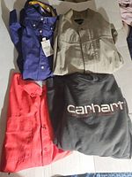 Four men's tops displayed: blue shirt with tags, beige zippered shirt, red button-up shirt, and black Carhartt sweatshirt.