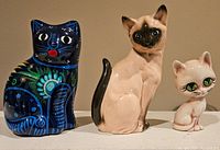 Three vintage ceramic cat figurines displayed side by side showing front view.