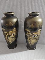 Pair of vintage Japanese etched brass vases with detailed pagoda and mountain scene, standing upright
