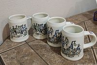 Four vintage ceramic mugs with colorful Dutch-themed illustrations and striped handles, arranged on floor tiles
