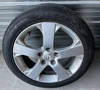 Photo of silver 5-spoke Mazda alloy wheel with tire mounted