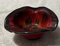 View of the abstract glass ashtray from an oblique angle showing its wavy rim and coloration.