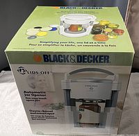 Photo of Black & Decker Lids Off automatic jar opener in box showing the device and jars with different lids illustrating use.