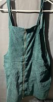 Front view of green corduroy dress showing wide straps and front zipper