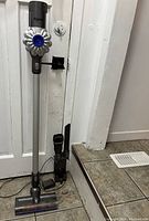 Full view of vacuum assembled on charging dock with extension wand and floor cleaning head