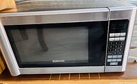 Full view of Emerson microwave oven showing stainless steel body, door with window, and digital control panel on right.