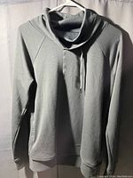 Grey hoodie sweatshirt hanging on white hanger showing the front side.