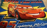 Large beach towel with Lightning McQueen image and 'Speed. I Am Speed.' text in vibrant colors.