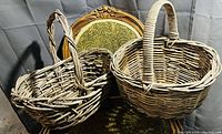Pair of rustic woven baskets shown side by side on a green ornate chair, highlighting their distinct shapes and rustic construction.