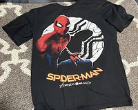 Front graphic of black Spider-Man Homecoming T-shirt featuring Spider-Man and spider logo with text.