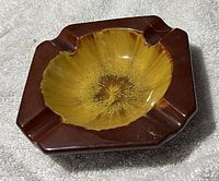 Single photo of a square Yellow Mountain Pottery ashtray with yellow glazed interior and dark brown exterior with four cigarette rests.